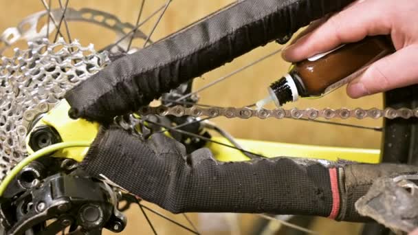 Primer plano en un taller de reparación de bicicletas el maestro lubrica la cadena con grasa. Reparación de bicicletas — Vídeos de Stock