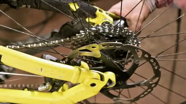 Close-up em uma loja de reparação de bicicletas, um mestre remove uma roda para manutenção. Reparação de bicicletas — Vídeo de Stock