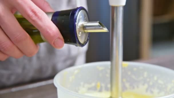 Hautnah die Mischung aus hausgemachter Mayonnaise mit einem Mixer in einer Plastikschüssel aufschlagen. Olivenöl — Stockvideo