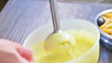 Plastik bir kabın içinde bir blender ile ev yapımı mayonez kırbaçlanan yakın çekim