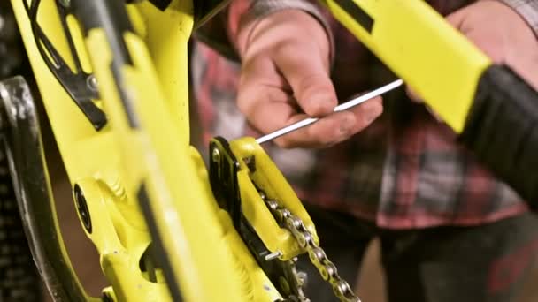 Manutenzione da vicino di una mountain bike. Le mani maschili regolano la tensione della catena. Monitoraggio delle condizioni tecniche in officina — Video Stock