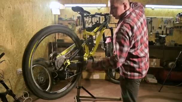 En cykel tekniker reparerar en mountain bike hjul på en bänk i en cykel verkstad. Cykel reparation — Stockvideo