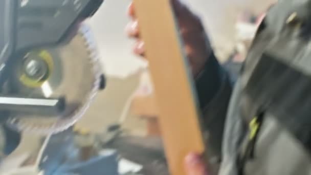 Concentrated young bearded joiner in goggles and a cap checks the workpiece for suitability while holding it in his hands and examining — Stock Video