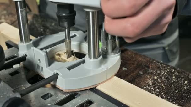 Primer plano de la mano de un carpintero que trabaja con un cortador eléctrico manual en un taller casero. Acabado de piezas de madera — Vídeo de stock
