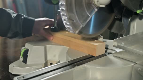 Primer plano de una mano de hombre trabajando en una máquina con una sierra circular. Corte de palanquilla de madera máquina circular — Vídeo de stock