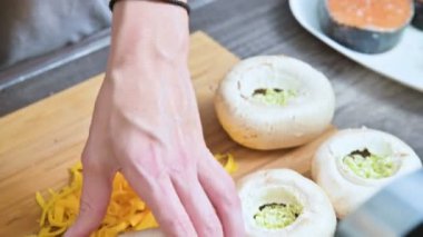 Erkek Close-Up doldurma taze porcini mantar sos ve bir protwin üzerine rendelenmiş peynir ile eller. Fırında mantar kavurma için hazırlık