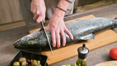 Eller Close-up büyük somon ev yemekleri, ahşap bir masa üzerinde bir bıçak ile kesme