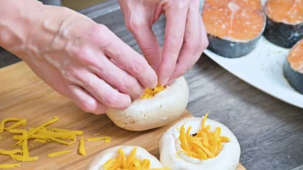 Primer plano de las manos femeninas relleno de hongos porcini frescos con salsa y queso rallado en un protwin. Preparación para asar en el horno de champiñones — Vídeos de Stock