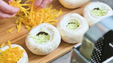 Erkek Close-Up doldurma taze porcini mantar sos ve bir protwin üzerine rendelenmiş peynir ile eller. Fırında mantar kavurma için hazırlık