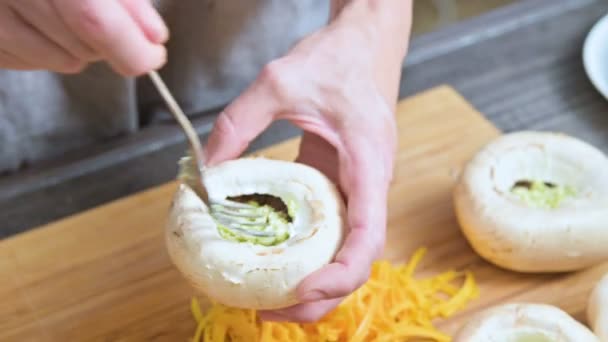特写镜头的女性手填充新鲜的波奇尼蘑菇与酱汁和磨碎的奶酪上的一个亲。蘑菇烤箱烤制的准备 — 图库视频影像