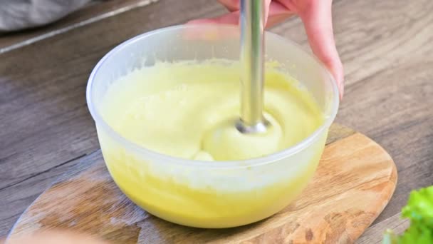 Gros plan fouetter la mayonnaise maison avec un mélangeur dans un bol en plastique — Video