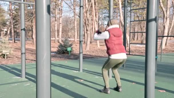 Porträt eines sportlichen Mädchens mit Wintermütze und warmem Gelb, das an einem sonnigen Tag im Winter die Übungen auf dem Trainingspad macht. Workout und Sport das ganze Jahr über — Stockvideo