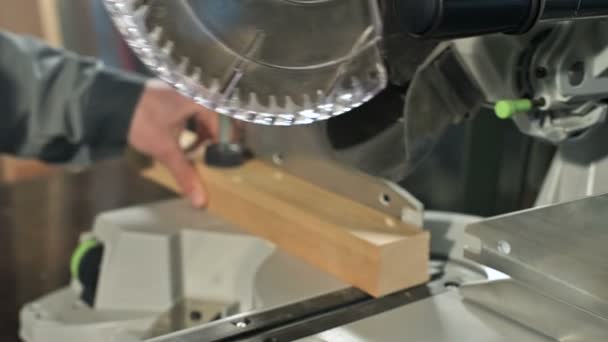 Primer plano de una mano de hombre trabajando en una máquina con una sierra circular. Corte de palanquilla de madera máquina circular — Vídeo de stock