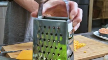 Erkek Close-up sürtünme peynir metal rende üzerinde eller. Ev mutfakta yemek