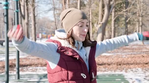 Retrato de uma menina de esportes fazendo aquecimentos ao ar livre no campo de esportes em um dia ensolarado no inverno — Vídeo de Stock