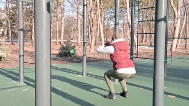 Porträt eines sportlichen Mädchens mit Wintermütze und warmem Gelb, das an einem sonnigen Tag im Winter die Übungen auf dem Trainingspad macht. Workout und Sport das ganze Jahr über — Stockvideo