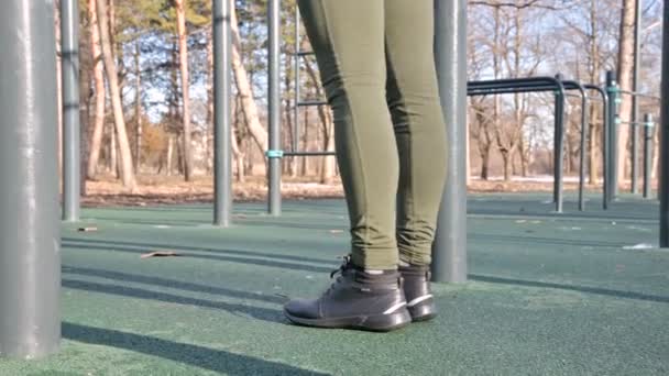 Close-up de pernas meninas na área aberta para o treino. Mulher sacode a imprensa pendurada na barra horizontal — Vídeo de Stock