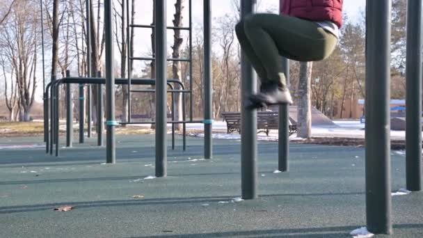 Detail dívky nohy na otevřeném prostoru pro cvičení. Žena třese tisk visí na hrazdě — Stock video