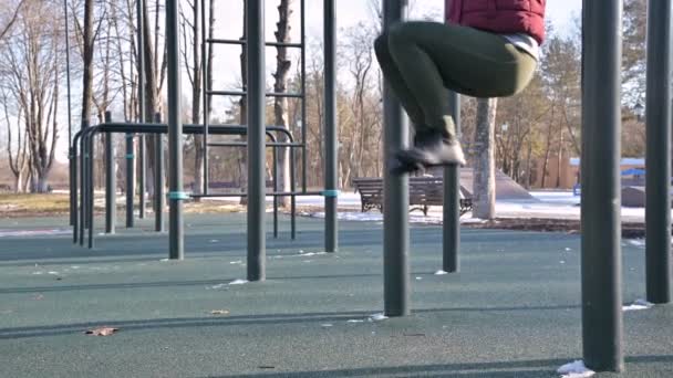 Close-up of girls legs on the open area for workout. Woman shakes the press hanging on the horizontal bar — Stock Footage Close-up of girls legs on the open area for workout. Woman shakes the press hanging on the horizontal bar Stock Video