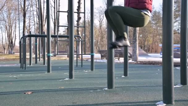 Close-up de pernas meninas na área aberta para o treino. Mulher sacode a imprensa pendurada na barra horizontal — Vídeo de Stock