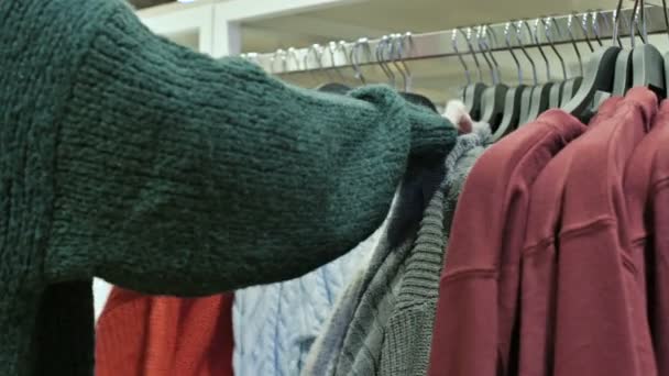 Primer plano de una mano de las niñas en una tienda elegir la ropa que cuelga de perchas para la venta — Vídeos de Stock