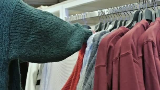 Close-up van de hand van een meisjes in een winkel die het kiezen van kleding hangers koop hangen — Stockvideo