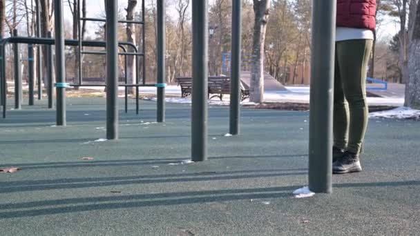 Close-up of girls legs on the open area for workout. Woman shakes the press hanging on the horizontal bar — Stock Footage Close-up of girls legs on the open area for workout. Woman shakes the press hanging on the horizontal bar Video Clip