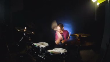 Uzun saçlı davulcu siyah bir zemin üzerine karanlık bir odada ayarla davul çalması bitinceye. Rock müzisyeni. Geniş açı