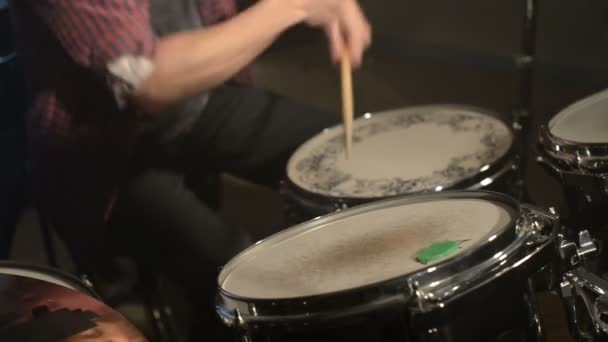 Dlouhé vlasy-bubeníci hrají bicí souprava v temné místnosti na černém pozadí. Rockový hudebník. Statický plán. Široký úhel — Stock video