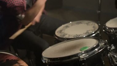 Uzun saçlı davulcular davul kiti karanlık bir odada bir siyah arka plan üzerinde oynamak. Rock müzisyeni. Statik plan. Geniş açı