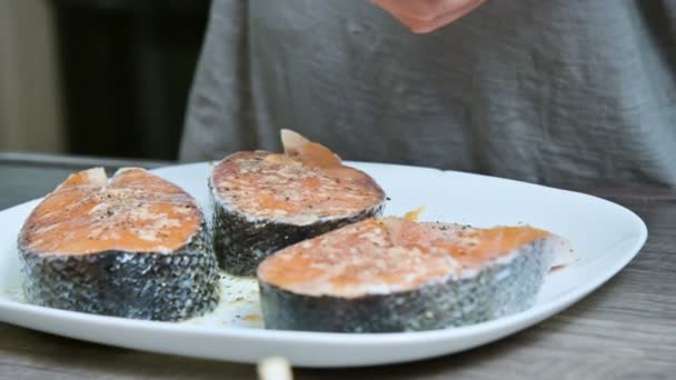 Close-up of the hands of a cook girl who prepares fresh fish salmon trout watering with lemon juice. Squeezes lemons hands. The concept of cooking healthy and vegan home cooking — Stock Video