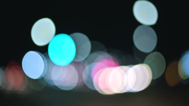 Luces bokeh de colores en la ciudad nocturna. círculos móviles de semáforos señales. Destacados noche desenfocada en la carretera de la ciudad — Vídeos de Stock