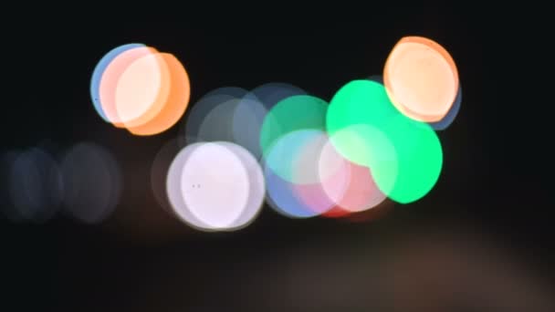 Luces bokeh de colores en la ciudad nocturna. círculos móviles de semáforos señales. Destacados noche desenfocada en la carretera de la ciudad — Vídeos de Stock