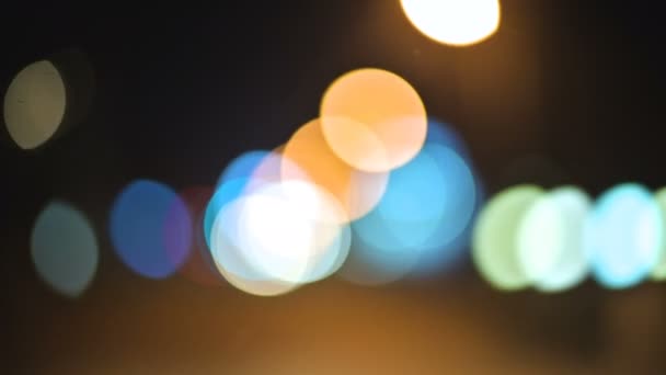 Luces bokeh de colores en la ciudad nocturna. círculos móviles de semáforos señales. Destacados noche desenfocada en la carretera de la ciudad — Vídeo de stock