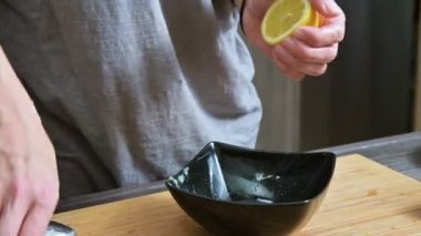 Sosu yapmak için siyah bir kapta limon kullanarak bir çatal ile yakın çekim kız sıkıyor