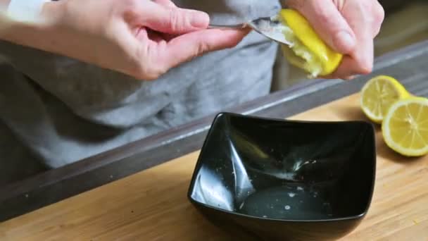 Close-up girl aprieta con un tenedor usando un limón en un tazón negro para hacer salsa — Vídeo de stock