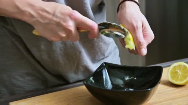 Close-up girl aprieta con un tenedor usando un limón en un tazón negro para hacer salsa — Vídeo de stock