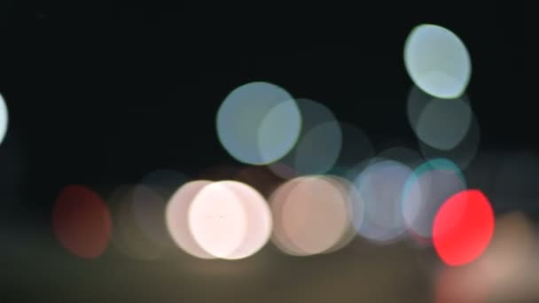 Luzes bokeh coloridas na cidade noturna. círculos móveis de semáforos sinais de luzes. Destaques noturnos desfocados na estrada da cidade — Vídeo de Stock