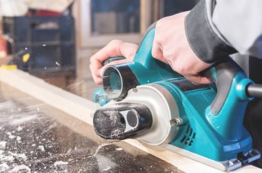 Bir marangoz ahşap elektrikli el aletleri Çalışma elleri. Elektrikli planya çalışmalarını yakın çekim