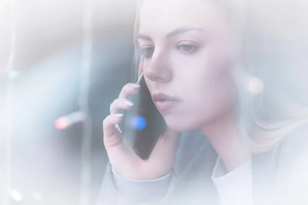 Zbliżenie portret atrakcyjna młoda dziewczyna rozmawia przez telefon. Non kontrast widok przez odbicie w kawiarni, w szkło gablotowe — Zdjęcie stockowe