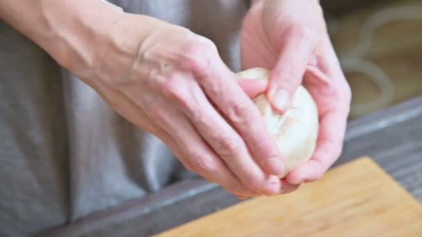 Die Großaufnahme weiblicher Hände einer Köchin in der heimischen Küche trennt die Beine von Pilzen von einem weißen Pilz. Zubereitung von Pilzen zum Backen — Stockvideo