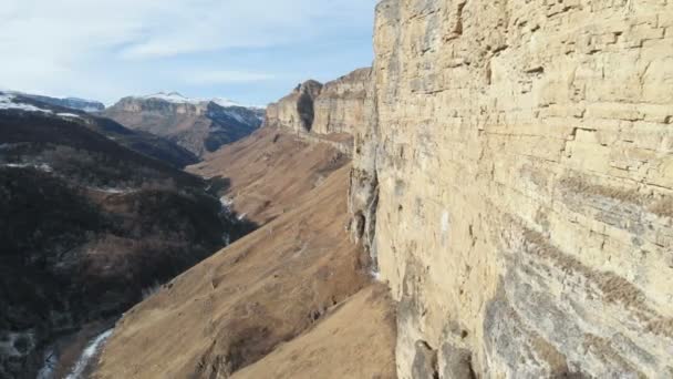 Veduta aerea del movimento lungo la parete rocciosa del canyon nella gola nel Caucaso. Molto vicino alla roccia in inverno quando c'è poca neve. 4k — Video Stock