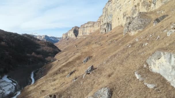 Vista aérea do movimento ao longo da parede rochosa do cânion no desfiladeiro no Cáucaso. Muito perto da rocha no inverno, quando há pouca neve. 4k — Vídeo de Stock