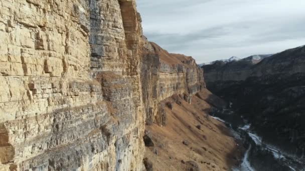 Veduta aerea del movimento lungo la parete rocciosa del canyon nella gola nel Caucaso. Molto vicino alla roccia in inverno quando c'è poca neve. 4k — Video Stock