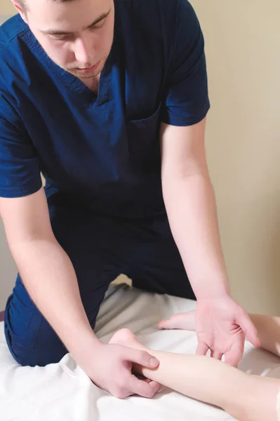 Detail z mužského chiropraktik ruce masážní lýtek malého pacienta. Malý chlapec na recepci postupu masáže v kanceláři fyzikální terapie — Stock fotografie