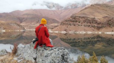 Havadan görünümü bir kayanın bir fotoğraf peyzaj telefonda alır ve bir video çekimleri bir göl üzerinde oturan bir kız. Seyahat video
