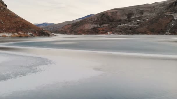 파란 시간 일몰 후 코 카 서 스 산으로 둘러싸인 겨울에 얼어붙은 호수를 통해 낮은 비행의 항공 보기 — 비디오