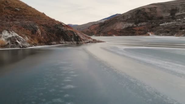 파란 시간 일몰 후 코 카 서 스 산으로 둘러싸인 겨울에 얼어붙은 호수를 통해 낮은 비행의 항공 보기 — 비디오
