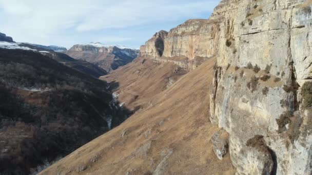 Vista aérea do movimento ao longo da parede rochosa do cânion no desfiladeiro no Cáucaso. Muito perto da rocha no inverno, quando há pouca neve. 4k — Vídeo de Stock