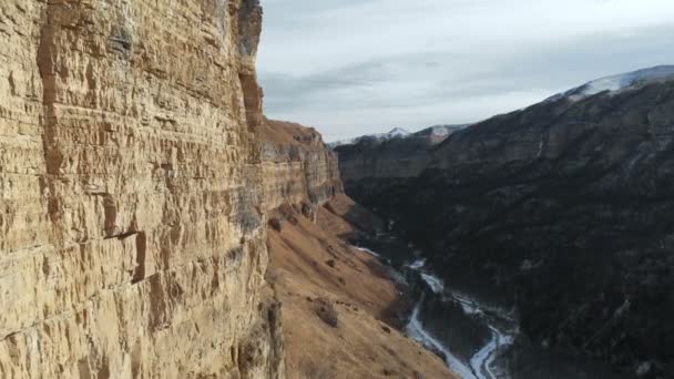 Veduta aerea del movimento lungo la parete rocciosa del canyon nella gola nel Caucaso. Molto vicino alla roccia in inverno quando c'è poca neve. 4k — Video Stock